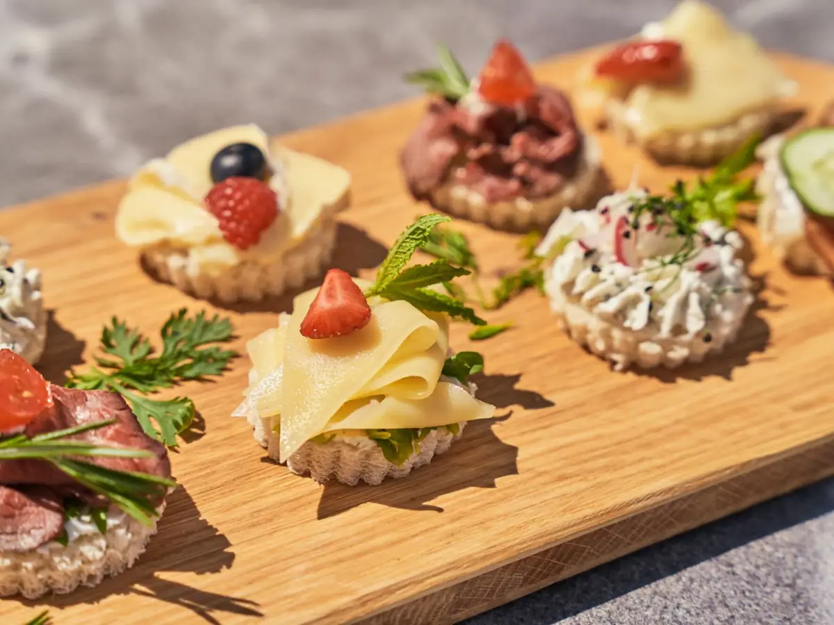 Canapés Ein Holzbrett mit kunstvoll angerichteten Canapés auf einem Tisch.