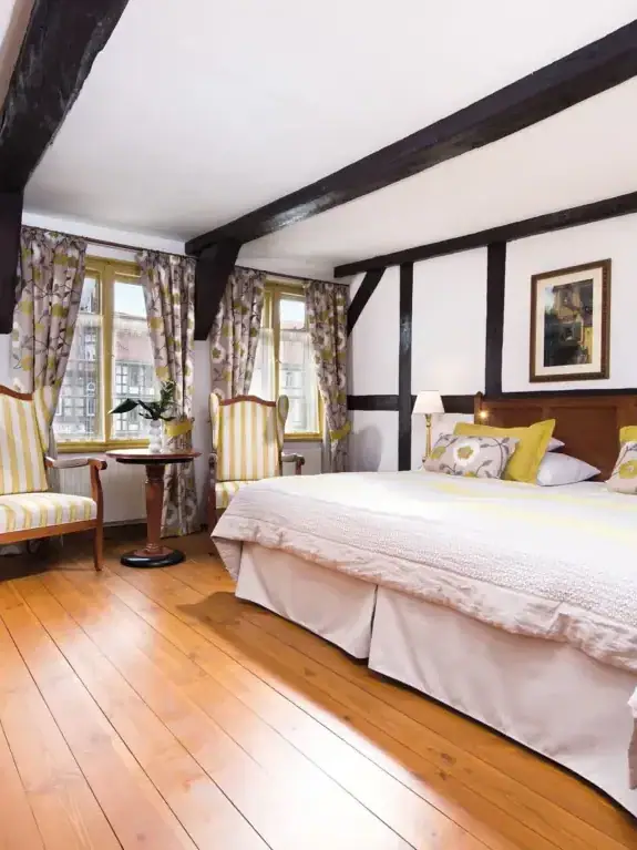 Zimmer & Suiten Ein Zimmer mit einem Bett und Stühlen.