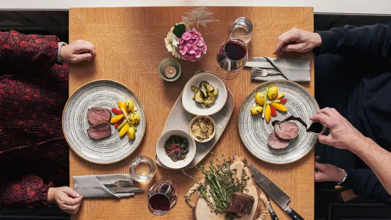 Eine Gruppe von Menschen sitzt an einem Tisch mit Tellern voller Essen.