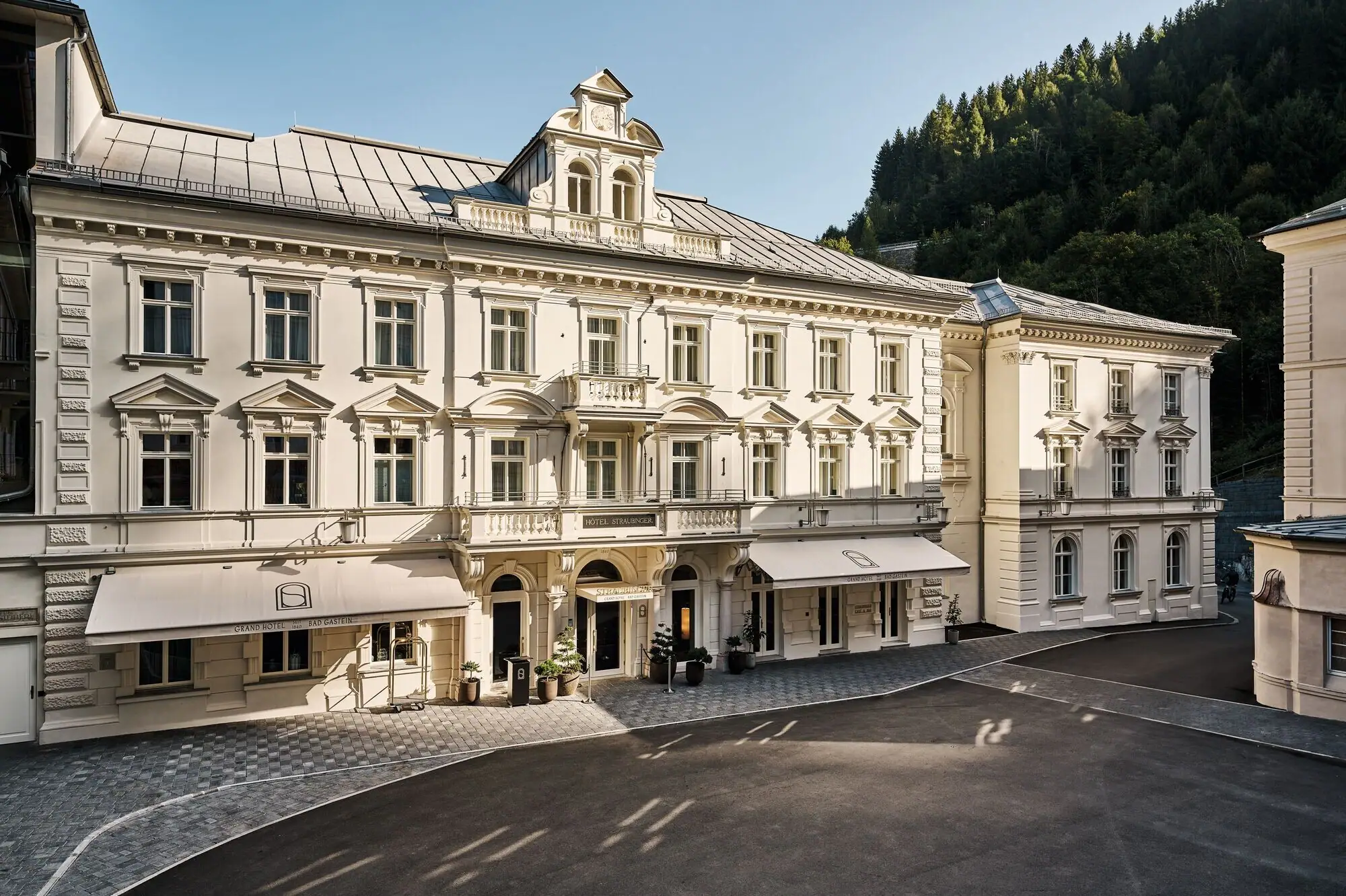 Großes weißes Gebäude mit gepflastertem Bereich im Vordergrund.