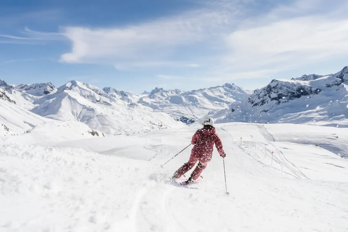 Skifahren Eine Person fährt auf Skiern einen schneebedeckten Berg hinunter.