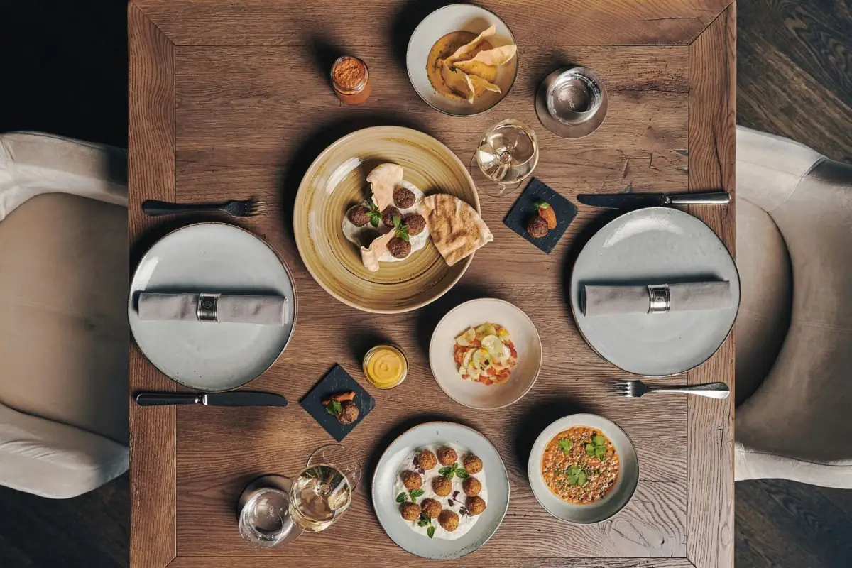 rische Vielfalt im Ifen Hotel Kleinwalsertal Ein gedeckter Holztisch mit Tellern voller Speisen aus der Vogelperspektive..