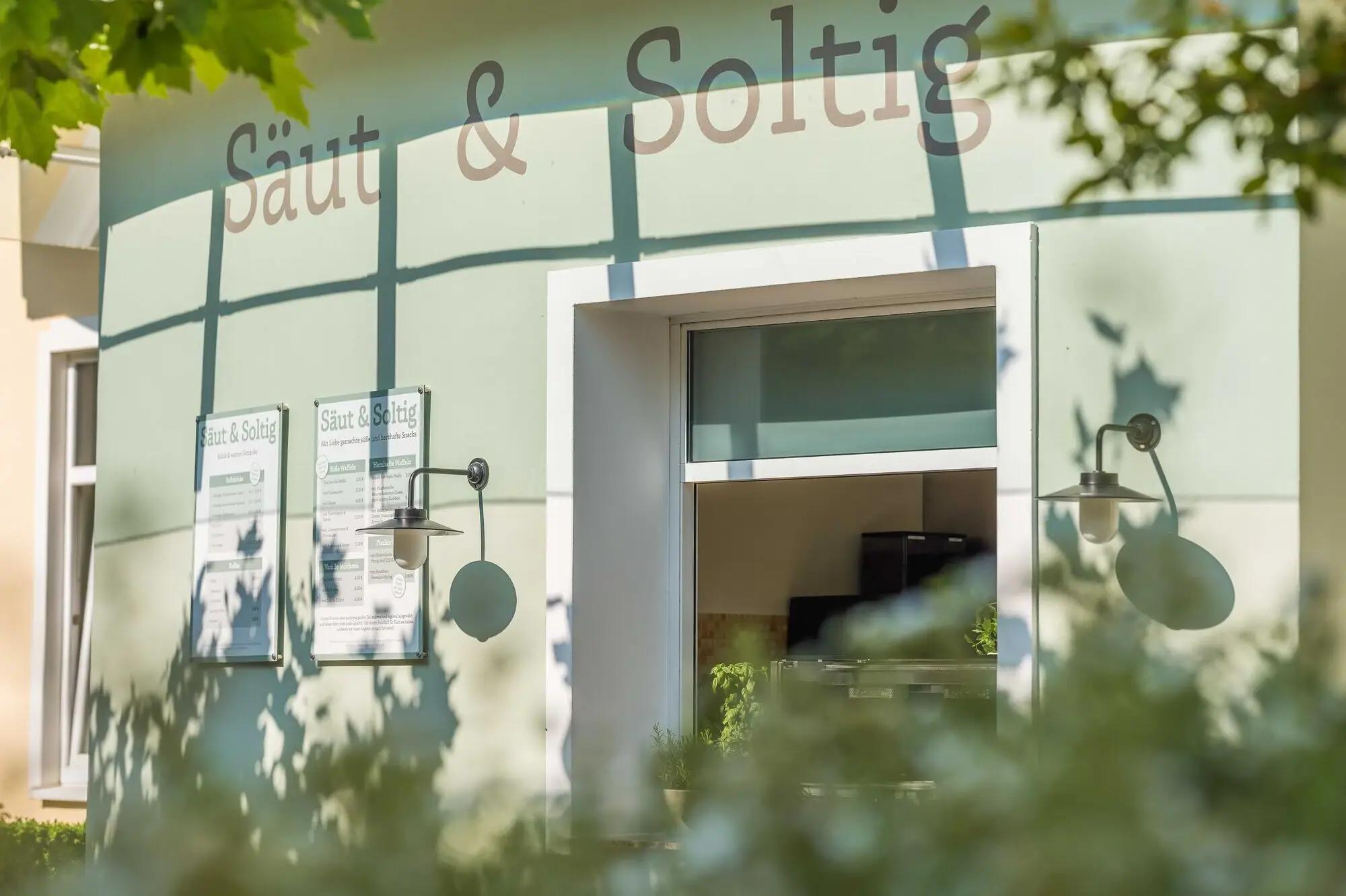 Bistro „Säut & Soltig“ im A-ROSA Ostseehotel Kühlungsborn Außenansicht des Bistros „Säut & Soltig“ mit Sonnenschein und grünen Blättern