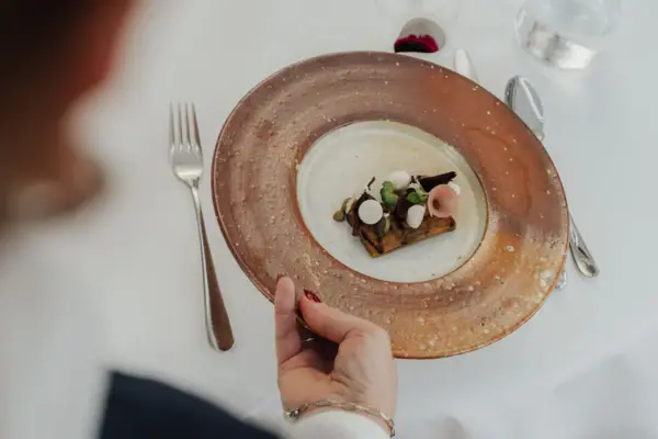 Eine Hand hält einen Teller mit Essen.