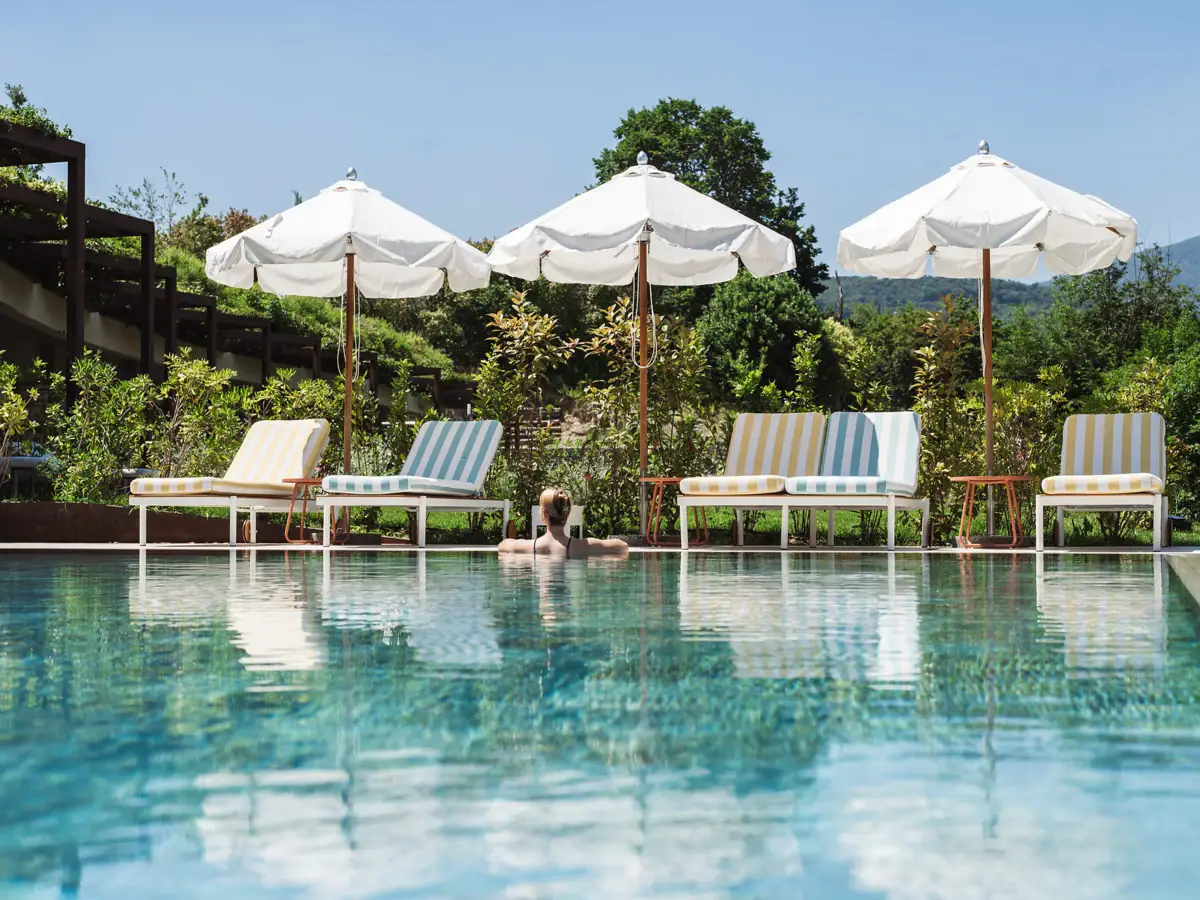 Außenpool vom A-ROSA Gardasee Eine Person im Pool mit Sonnenschirmen und Liegestühlen.