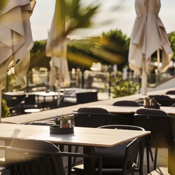 Ein Tisch und Stühle im Freien mit Sonnenschirmen und Bäumen.