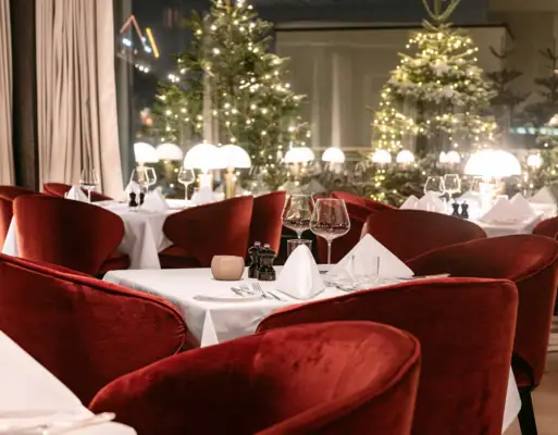 Gastronomie Ein Tisch mit roten Stühlen und weißer Tischdecke.