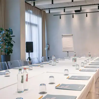 Konferenzraum mit weißen Tischen und Stühlen.