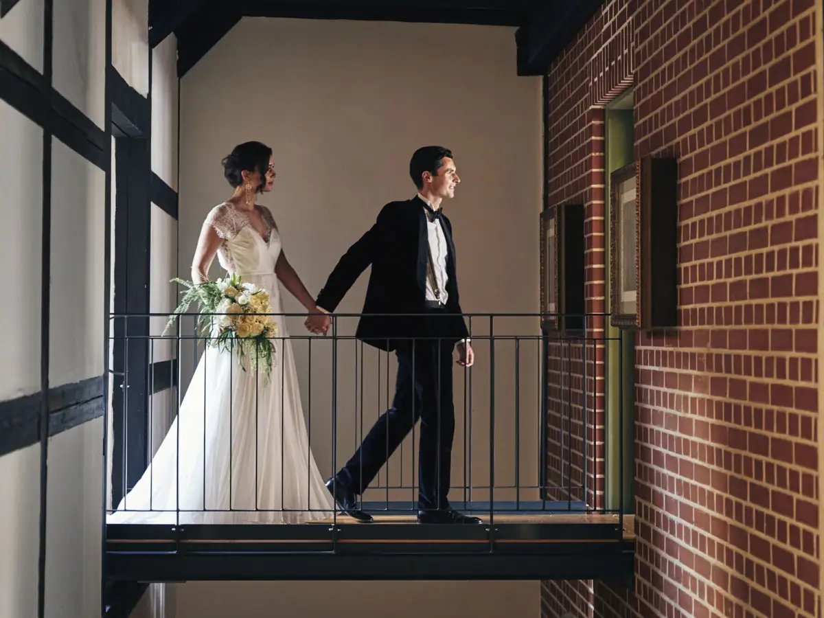 Hochzeitspaar Ein Mann und eine Frau in Hochzeitskleidung halten Händchen und gehen über einen Gang.