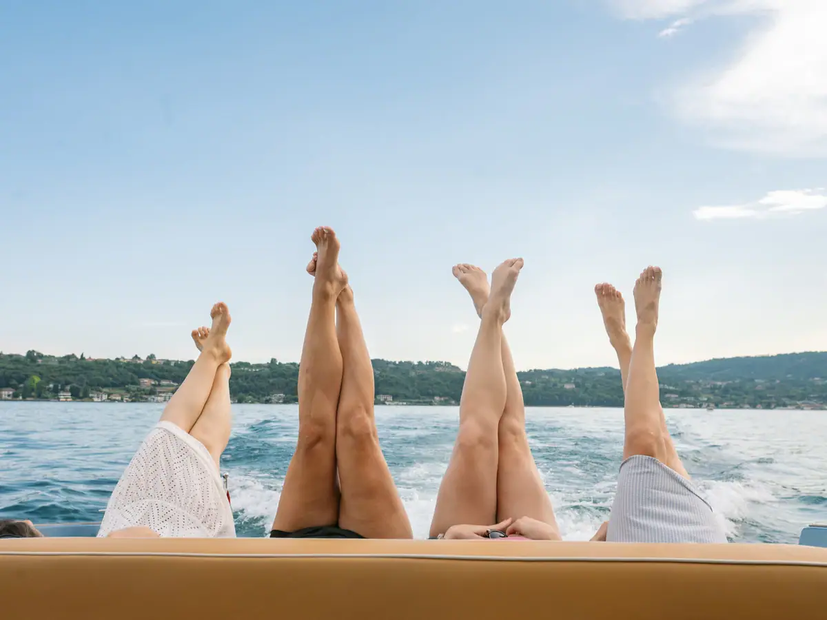 Teamspirit auf dem Wasser Vier Personen genießen eine entspannte Bootstour auf dem Gardasee und strecken die Beine in die Sonne.