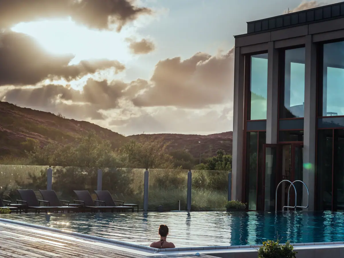Außenpool auf Sylt Eine Frau in einem Pool mit einem Gebäude im Hintergrund.