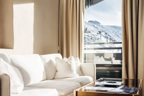 Weißes Sofa in einem Zimmer mit Couchtisch und verschneitem Berg im Hintergrund.