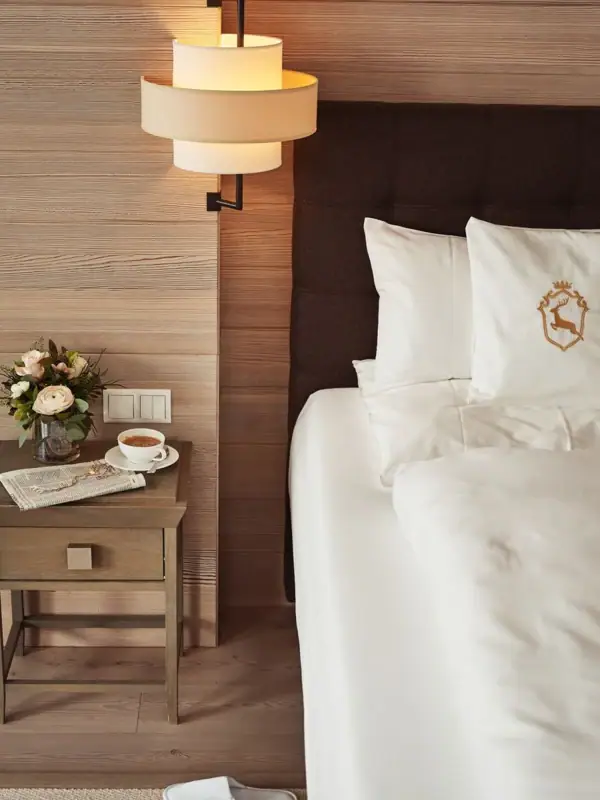 Ein Bett mit einer Tasse Kaffee und einer Vase mit Blumen auf einem Tisch.