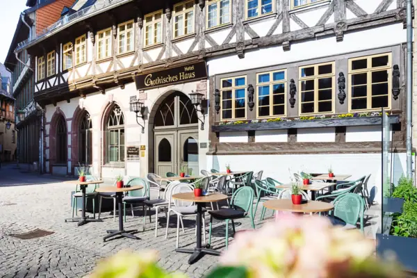 Gothisches Haus Ein Gebäude mit Tischen und Stühlen im Freien.