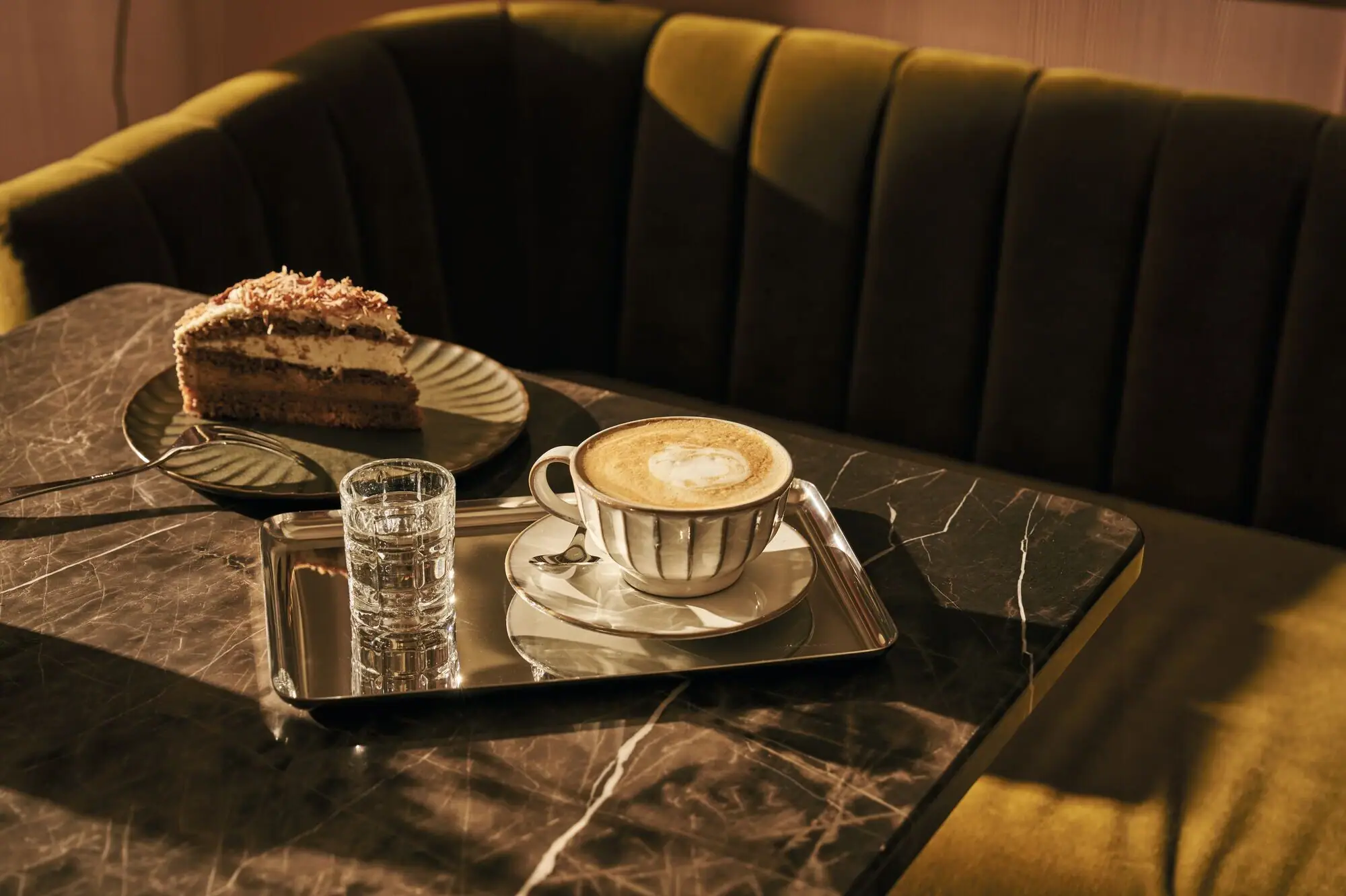 Kuchenzeit im Café Ein Kaffeegedeck mit Kaffeetasse, Tortenstück und Gabel auf einem Tisch.