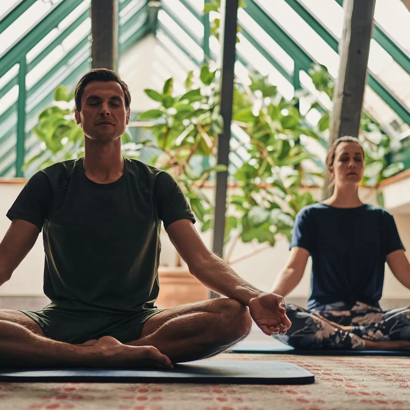 Ein Mann und eine Frau sitzen auf Yogamatten.