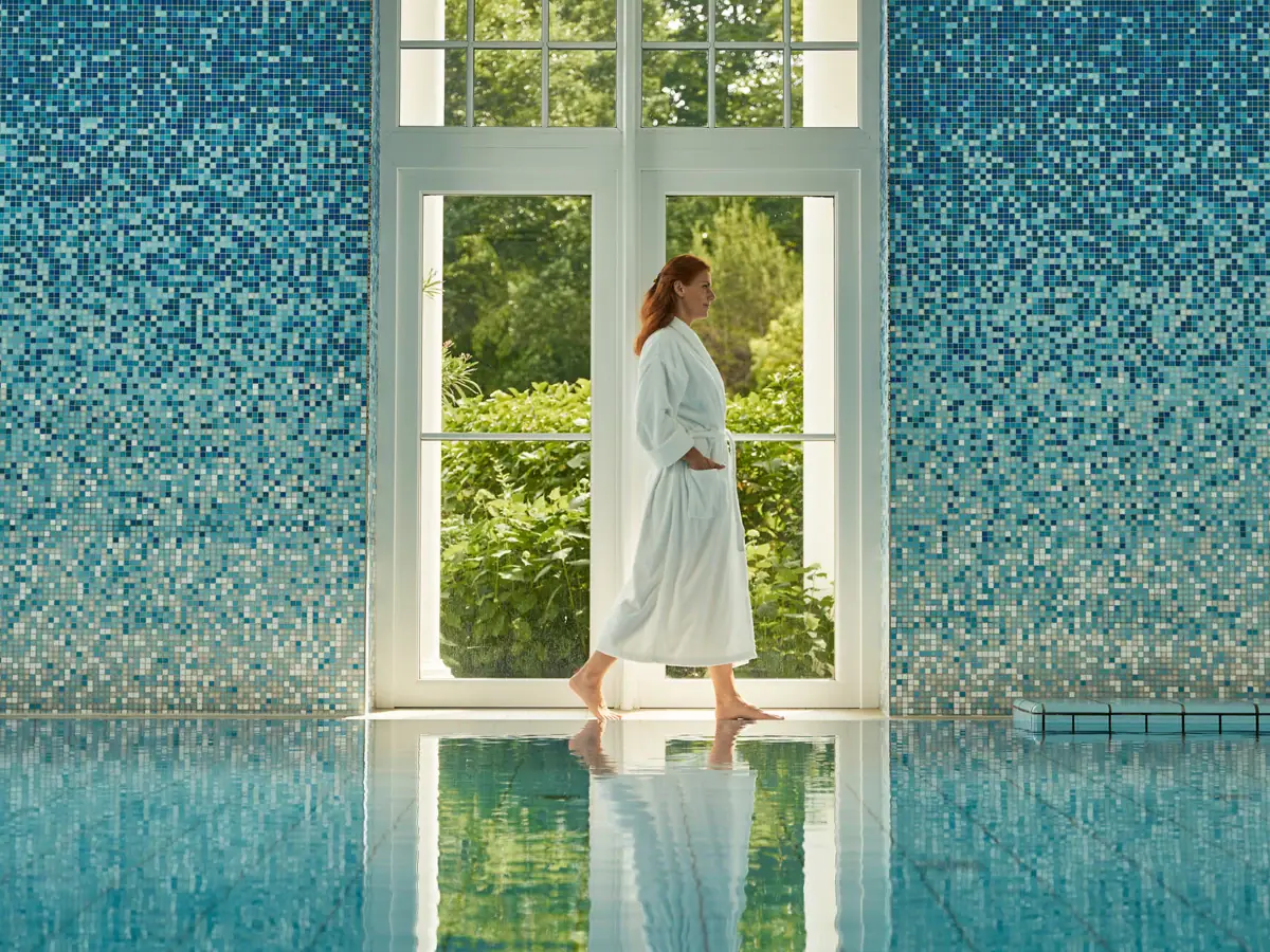 Innenpool Strandidyll Heringsdorf Eine Frau im weißen Bademantel geht in einem Pool.