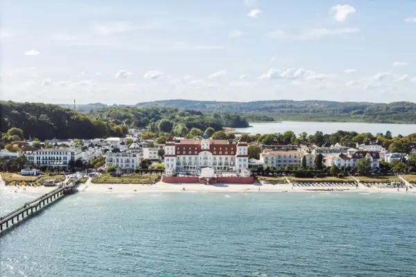 Kurhaus Binz Ein großes weißes Gebäude neben einem Gewässer.