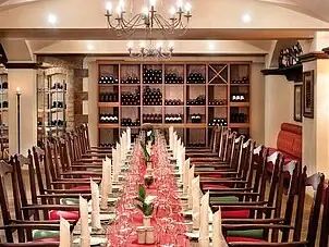 Weinkeller Ein Raum mit einem Tisch, der für eine Dinnerparty gedeckt ist, mit Kerzen und elegantem Interieur.