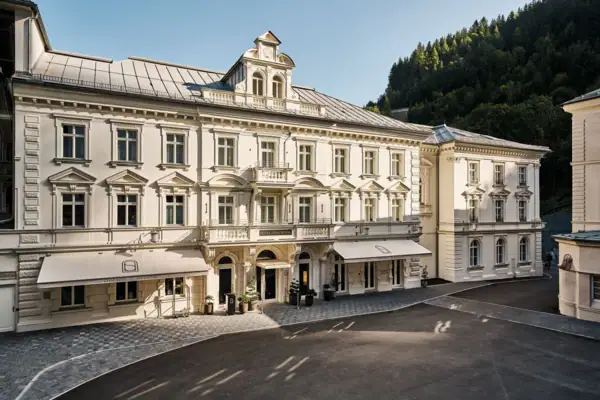 Straubinger Grand Hotel Großes weißes Gebäude mit Fenstern und gepflastertem Bereich im Vordergrund.