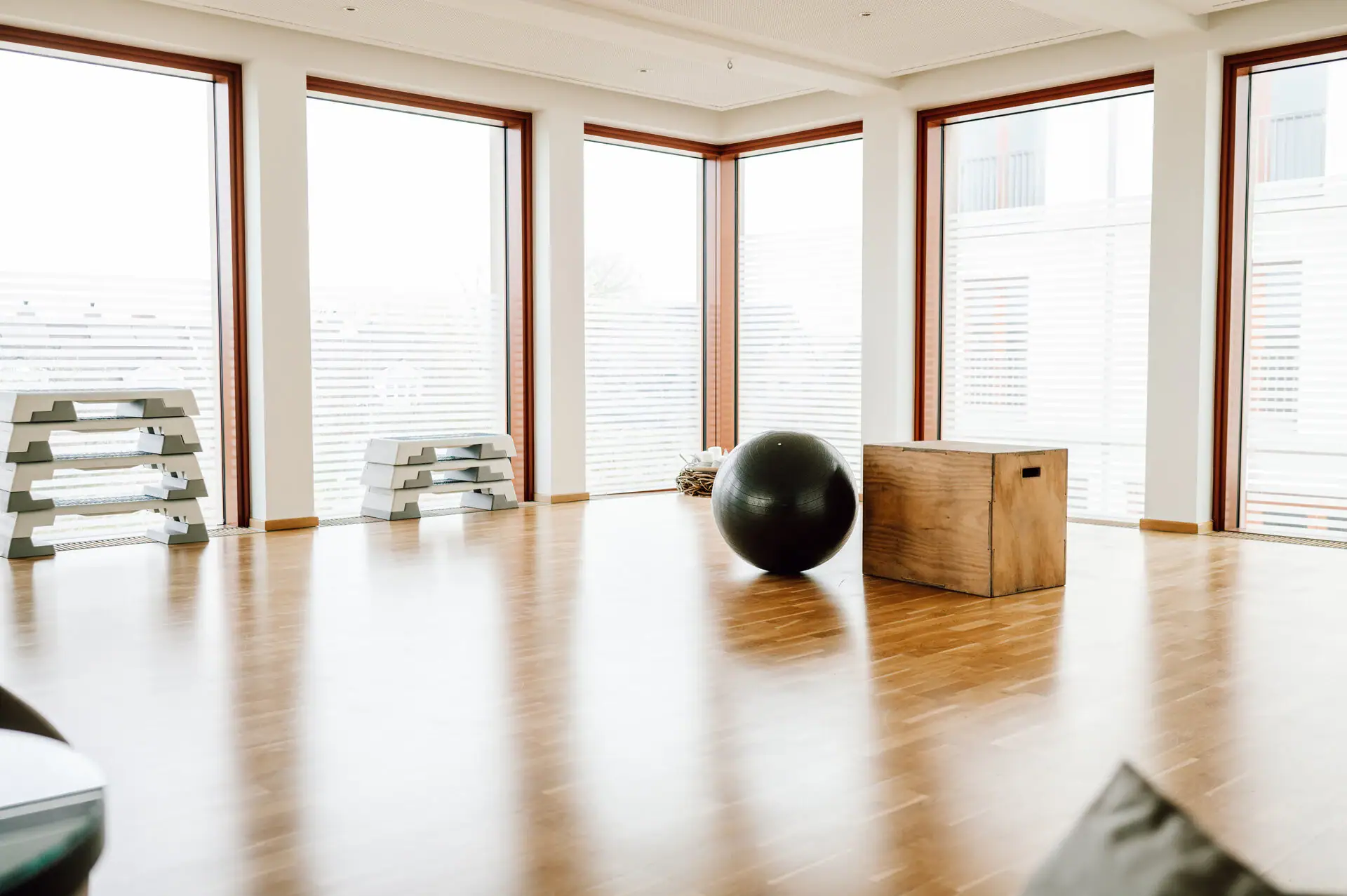 Trainingsraum Großer schwarzer Ball auf einem Holzboden in einem Raum mit Fenstern.