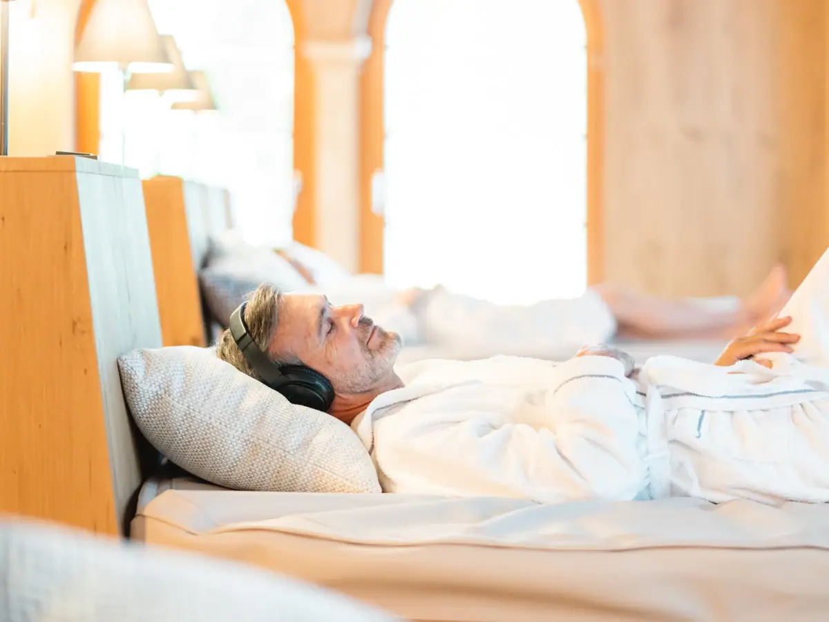 Ein Mann mit Kopfhörern liegt auf einem Bett.