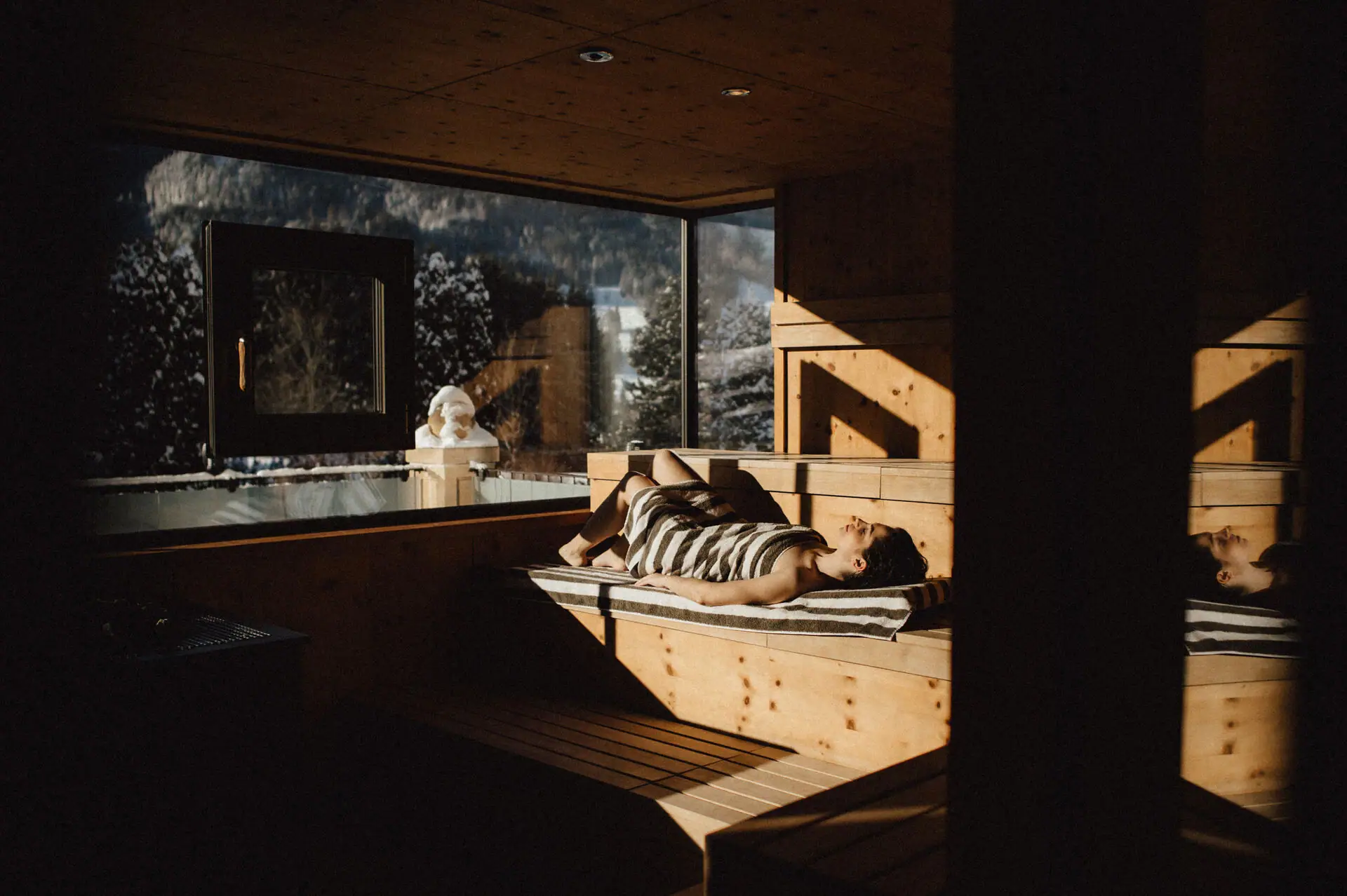 Person liegt auf einer Bank in einer Sauna.