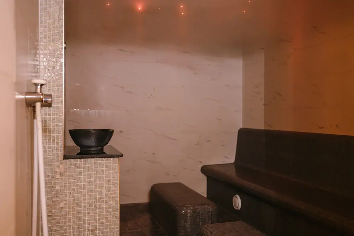 Caldarium auf Sylt Ein gefliestes Dampfbad mit einer Bank und einer Schale.
