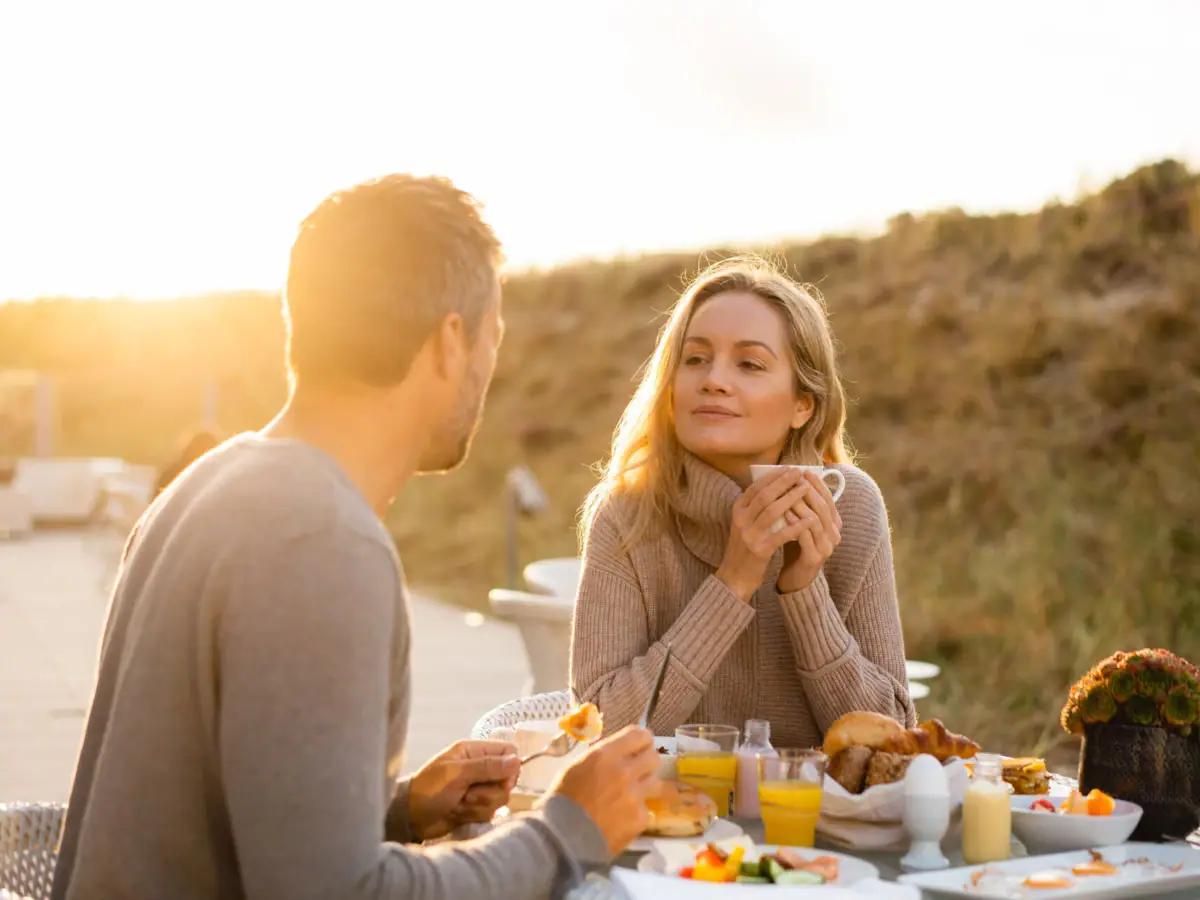 Frühstück auf der Terrasse Ein Mann und eine Frau sitzen an einem Tisch mit Essen.