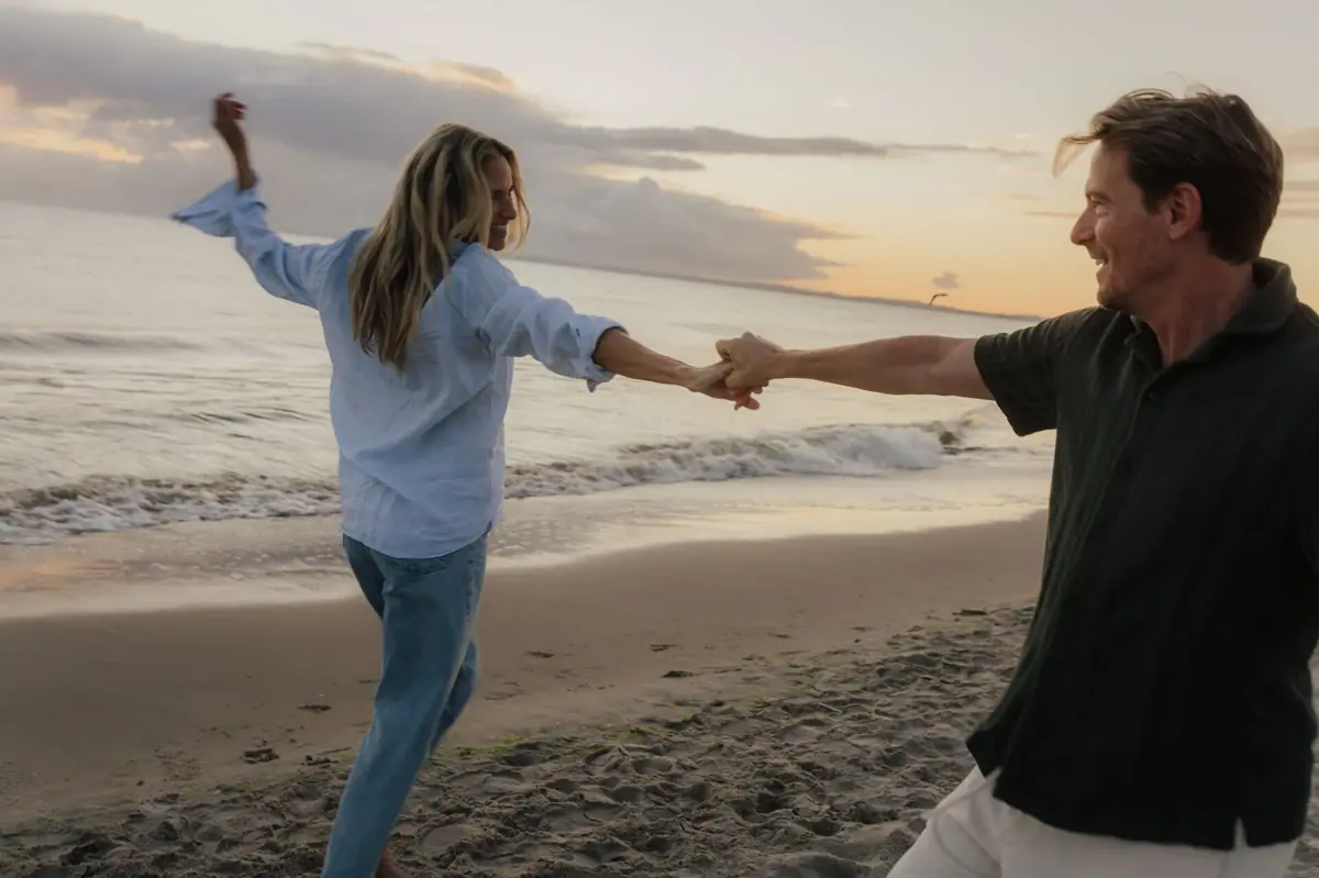 Paar am Strand Ein Mann und eine Frau halten sich an einem Strand an den Händen.