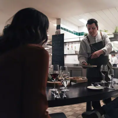 Ein Mann serviert einer Gruppe von Menschen Essen.