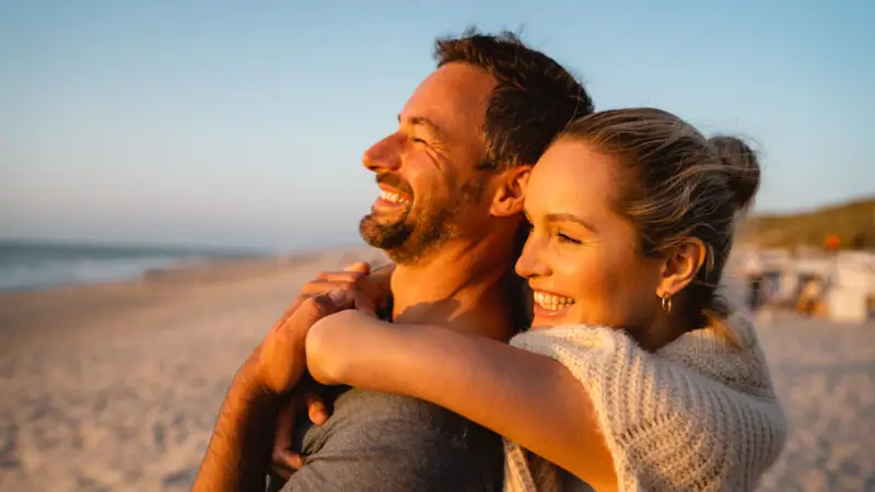Ein Mann und eine Frau umarmen sich am Strand.