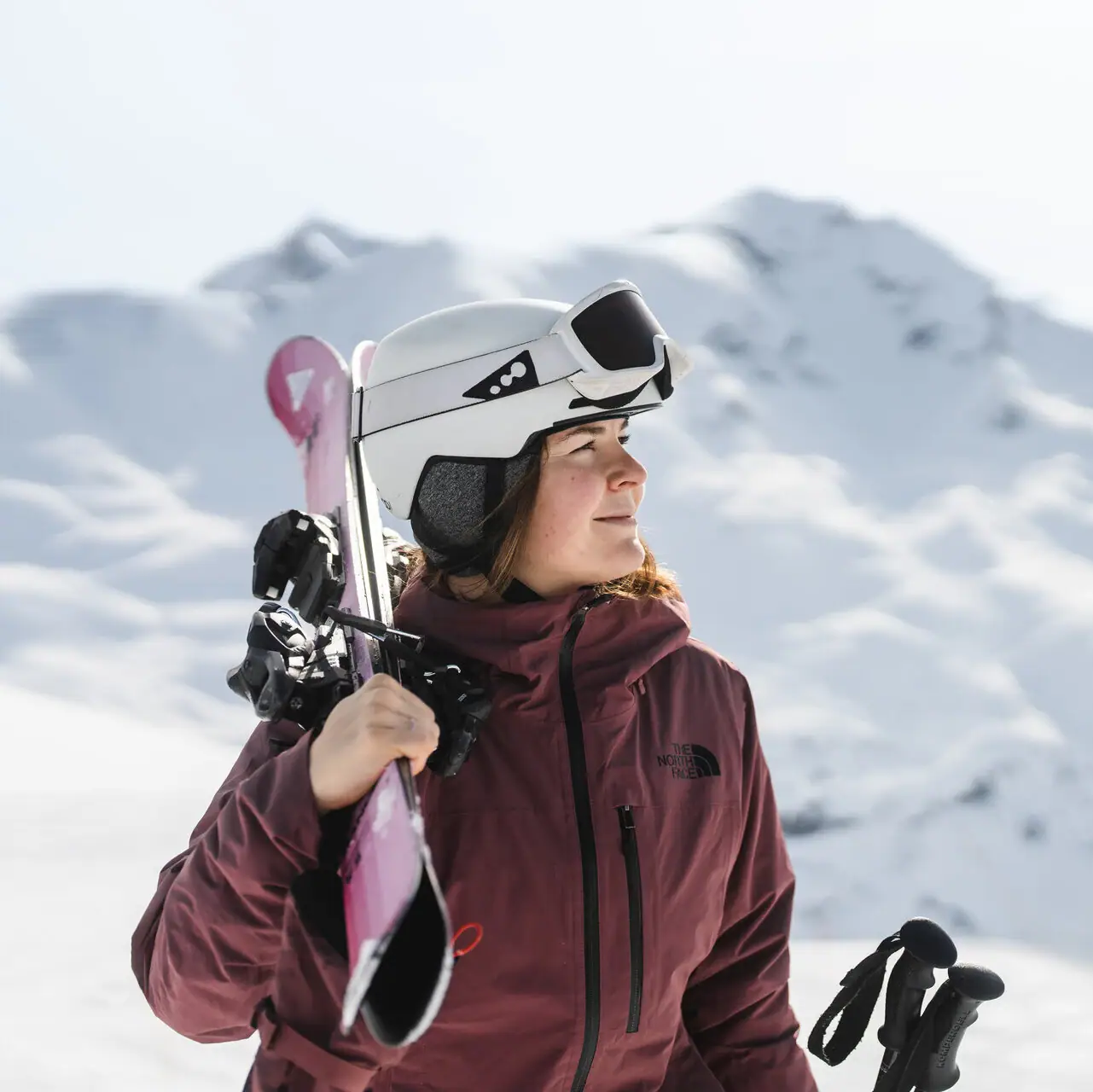 Frau hält einen Ski und Skistöcke im Freien bei Schnee.