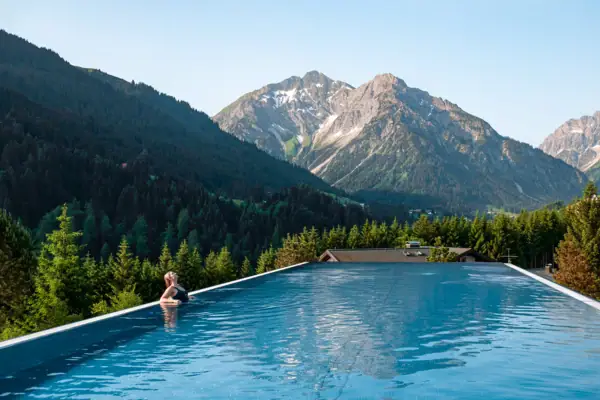 Eine Person in einem Pool mit Bergen im Hintergrund.