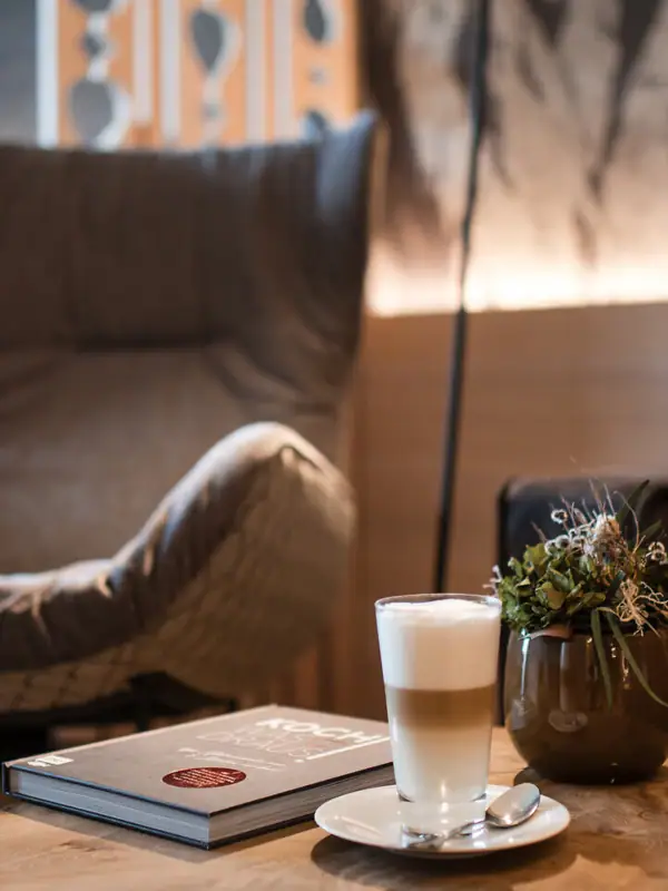 Ein Couchtisch mit einem Buch und einem Getränk darauf.