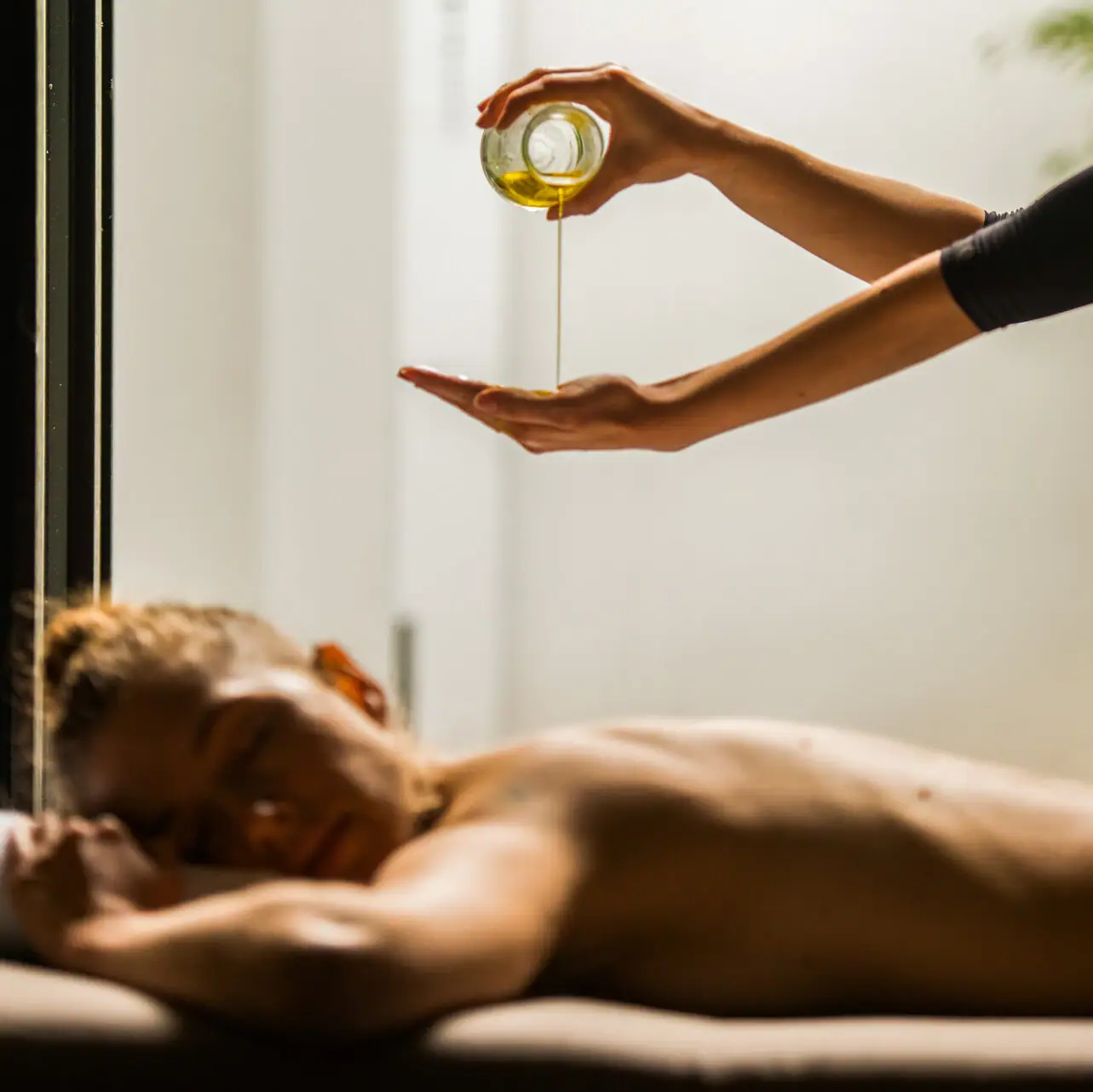 Eine Person gießt Öl in die Hand einer anderen Person.