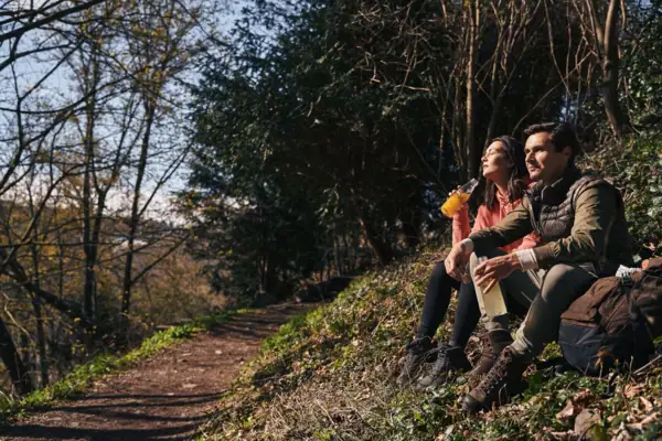 Ein Mann und eine Frau sitzen auf einem Felsen auf einem Wanderweg.