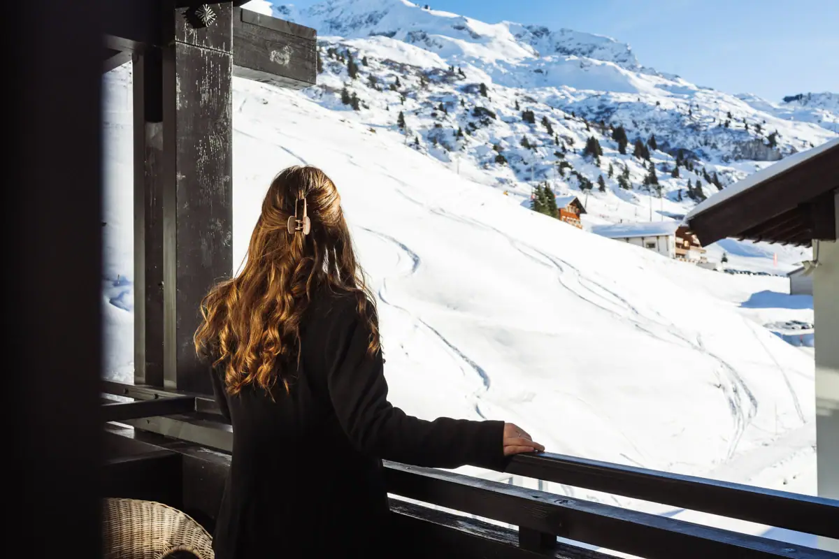 Ausblick vom Balkon Eine Frau blickt auf einen schneebedeckten Berg.