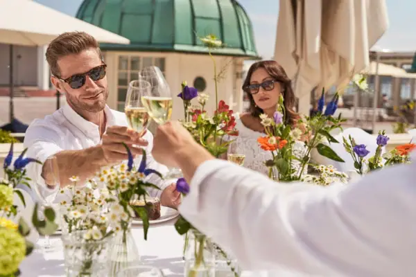 Eine Gruppe von Menschen sitzt an einem Tisch mit Blumen und Getränken.