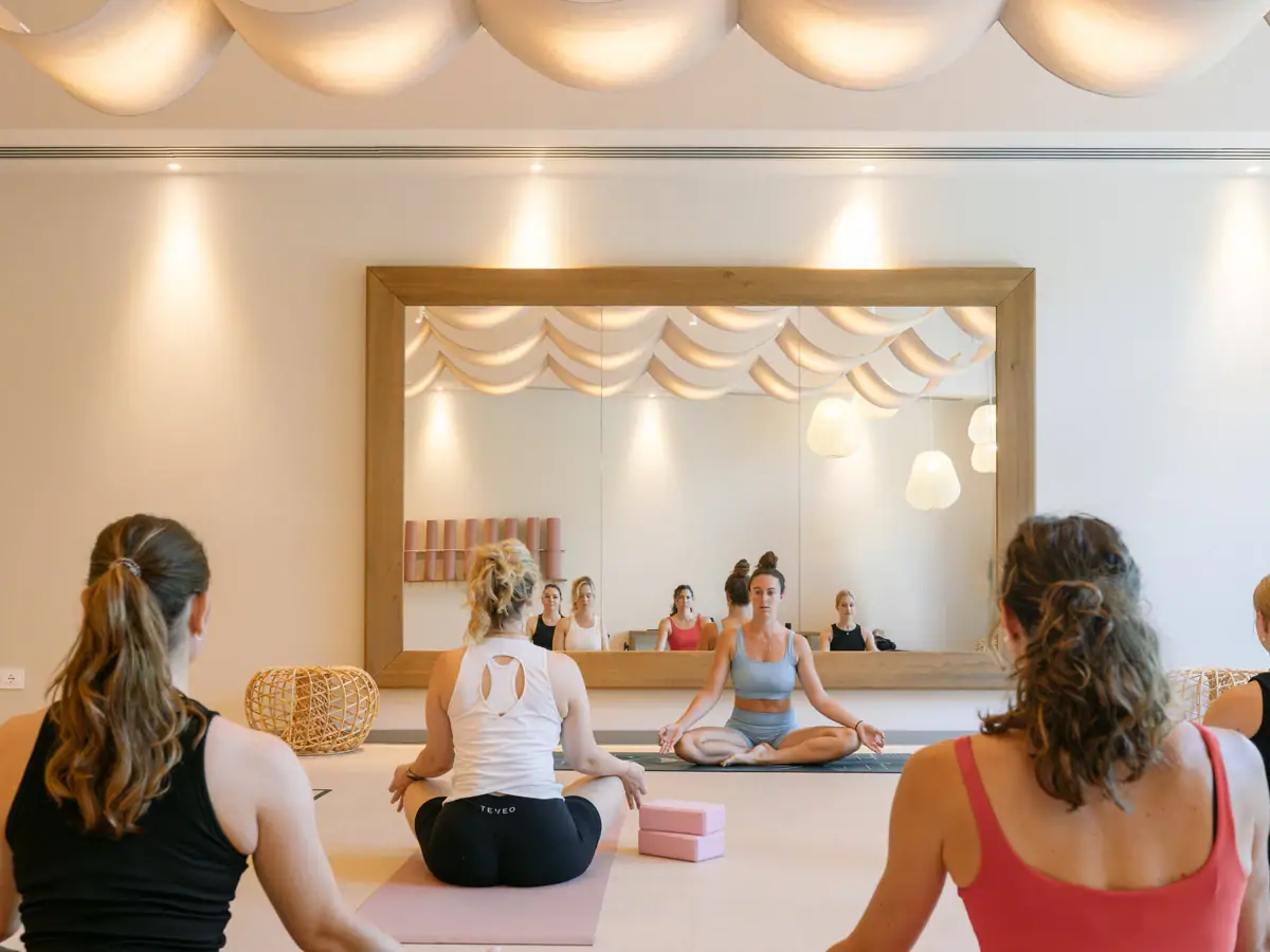 Eine Gruppe von Frauen sitzt in einem Raum mit einem Spiegel und praktiziert Yoga,