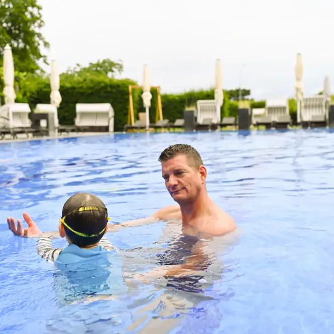 Ein Mann und ein Kind im Schwimmbecken.