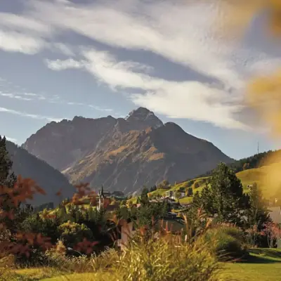 Landschaft eines Gebirgszugs mit Wolken und Pflanzen im Vordergrund.