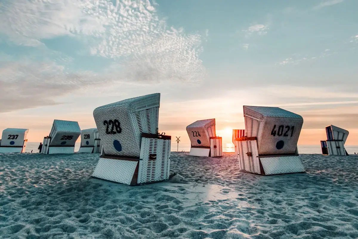 Weiße Strandkörbe auf Sand.