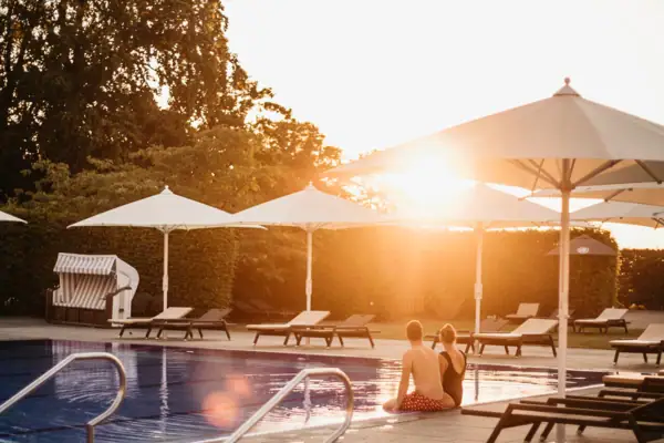 Außenpool A-ROSA Travemünde Ein Paar sitzt am Pool im Freien.
