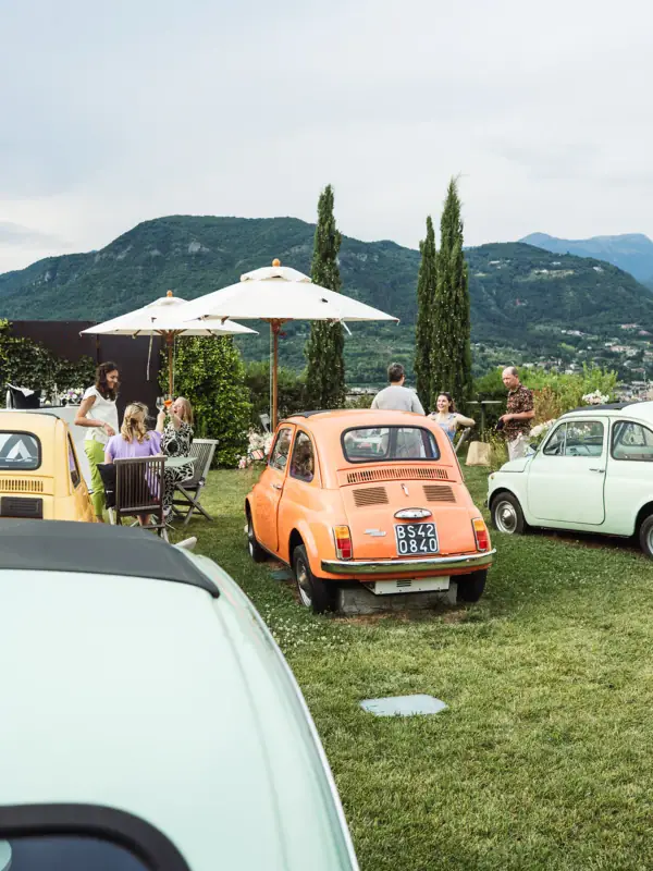 Fiat 500 Terrasse Eine Gruppe von Menschen sitzt um ein klassisches Auto im Freien.