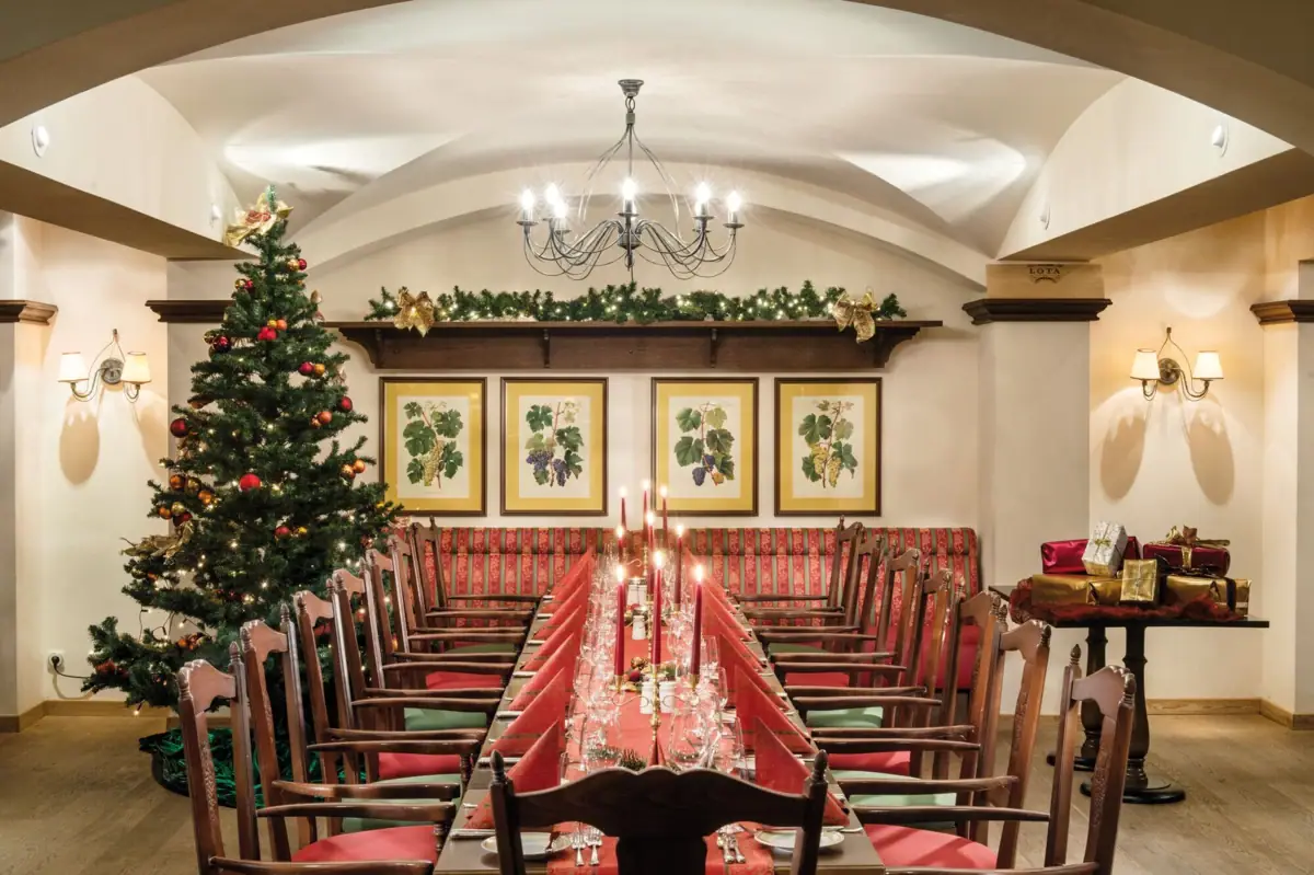 Winkeller Ein Zimmer mit einem Weihnachtsbaum und einem Tisch mit Stühlen.