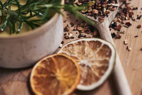 Dampfbad Travemünde Ein Löffel mit Gewürzen, Zitrusfrüchten und eine Schüssel mit Öl auf einer Holzoberfläche.