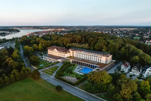 A-ROSA Travemünde Großes Gebäude mit Pool, umgeben von Bäumen.