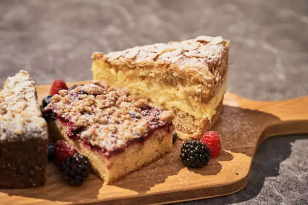 Ein Stück Kuchen mit Beeren auf einem Holzbrett.