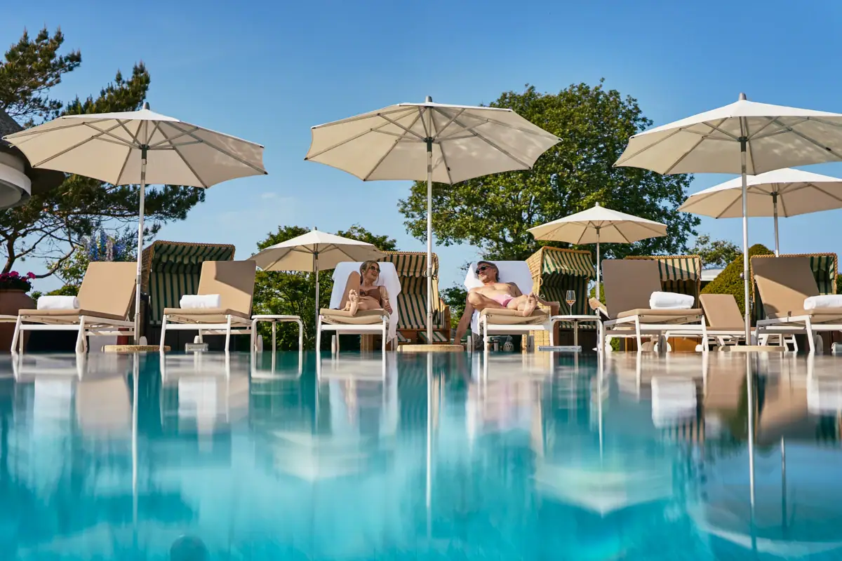 Eine Gruppe von Menschen sitzt auf Stühlen am Pool.